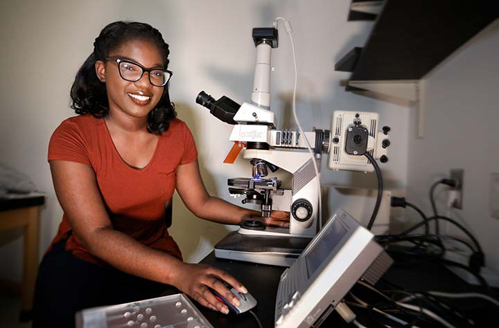 Alex Osuma in the lab looking into microscope.