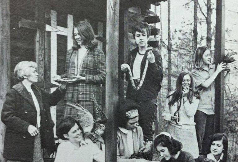 A group of women standing outside of the original anderson cabin in the arb