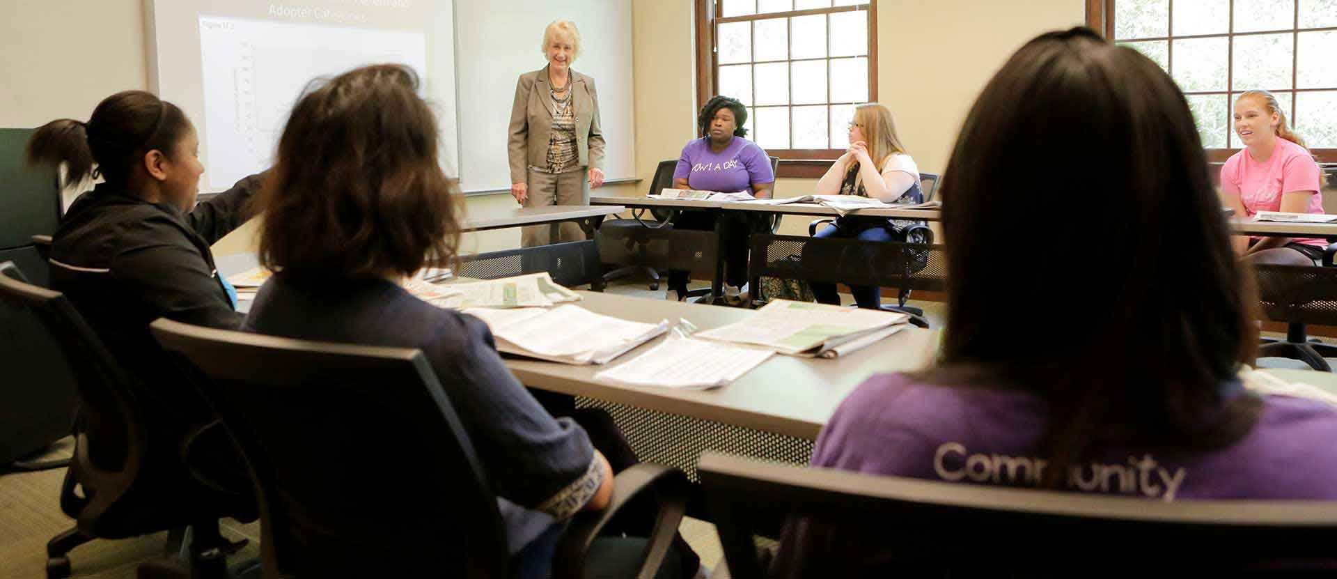 Professor has discussion with students on subject in the classroom