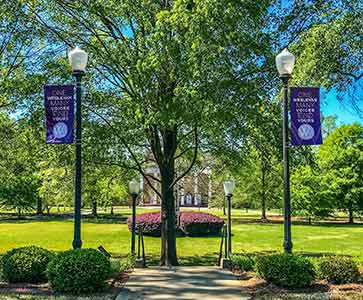 Campus view with 2 flags that say One Wesleyan Many Voices.