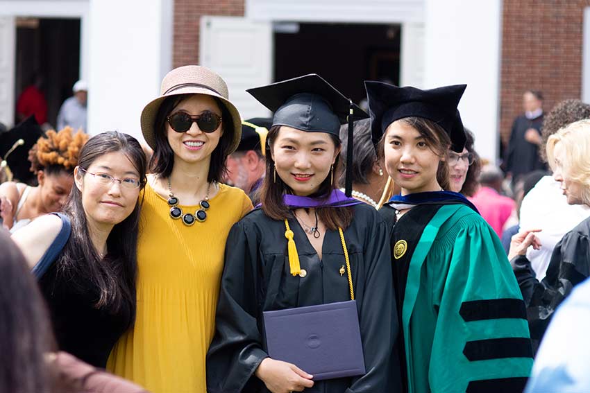 Graduate with professors after ceremony.