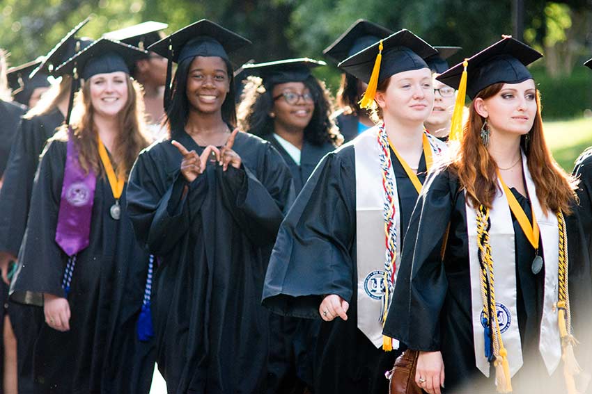 Students in robes walking from marker ceremony.